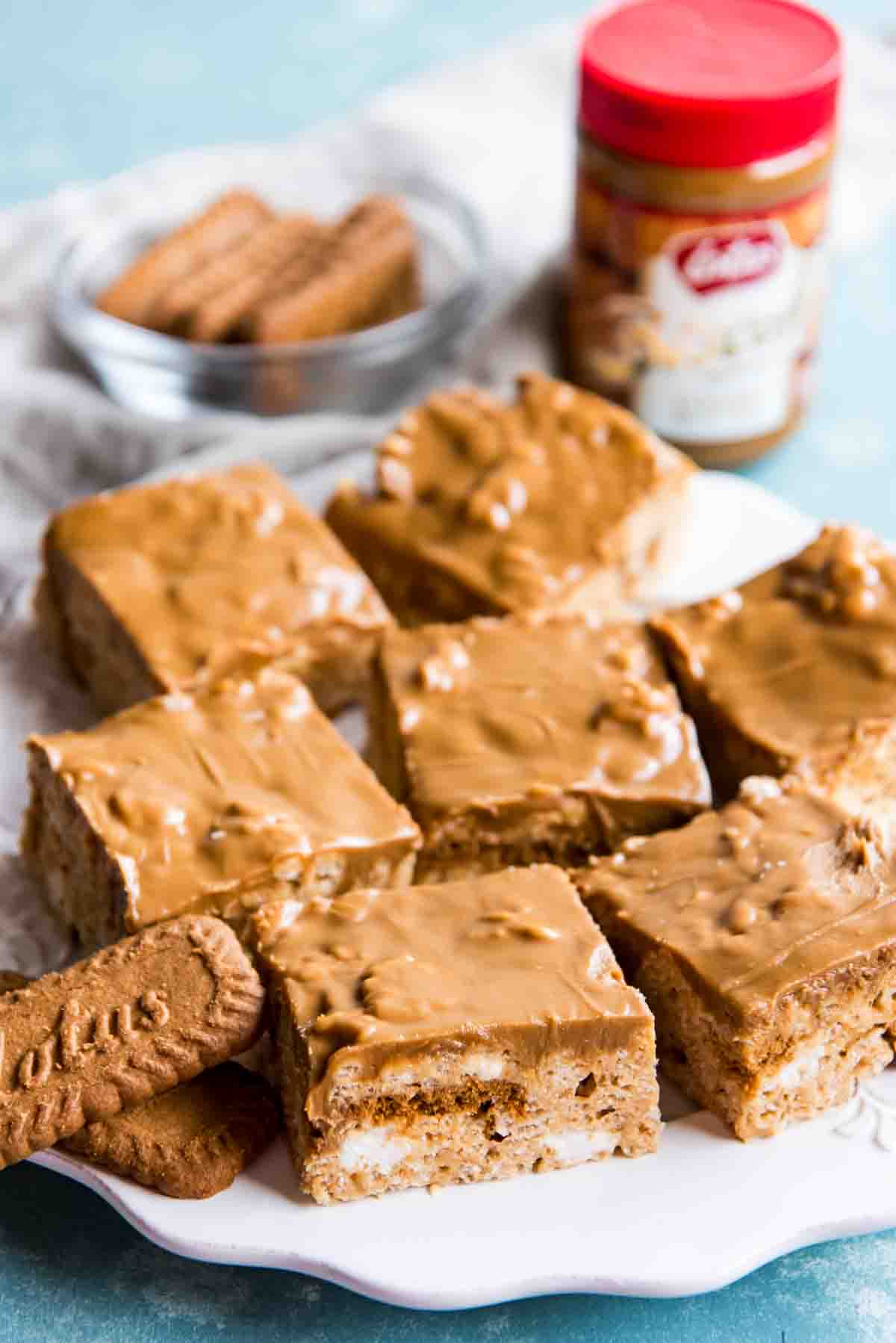 Above angle shot looking down at a white plate of rice krispie squares and biscoff cookie butter.