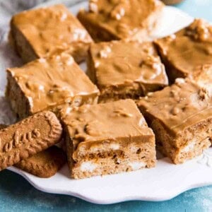 Above angle shot looking down at a white plate of rice krispie squares and biscoff cookie butter.