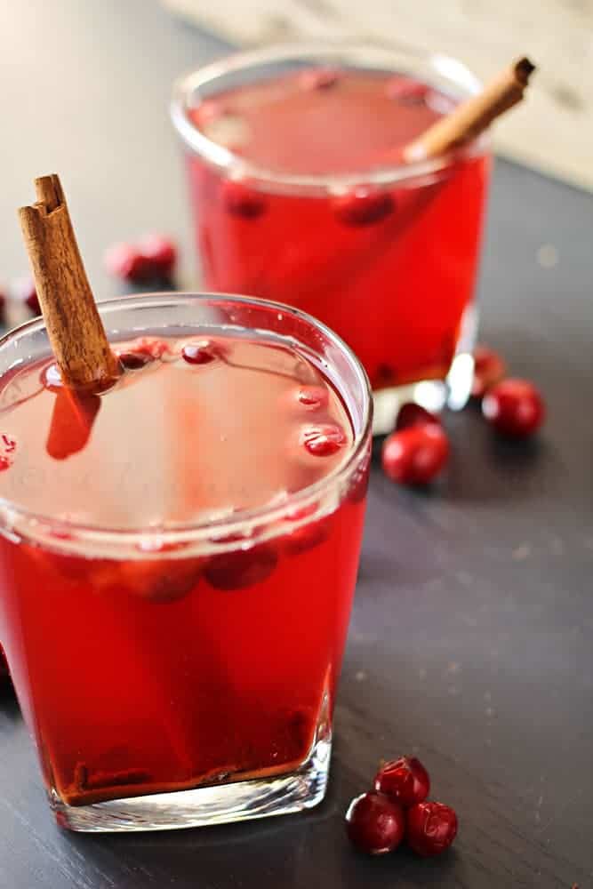 Cranberry cider in two glasses with fresh cranberries and cinnamon sticks