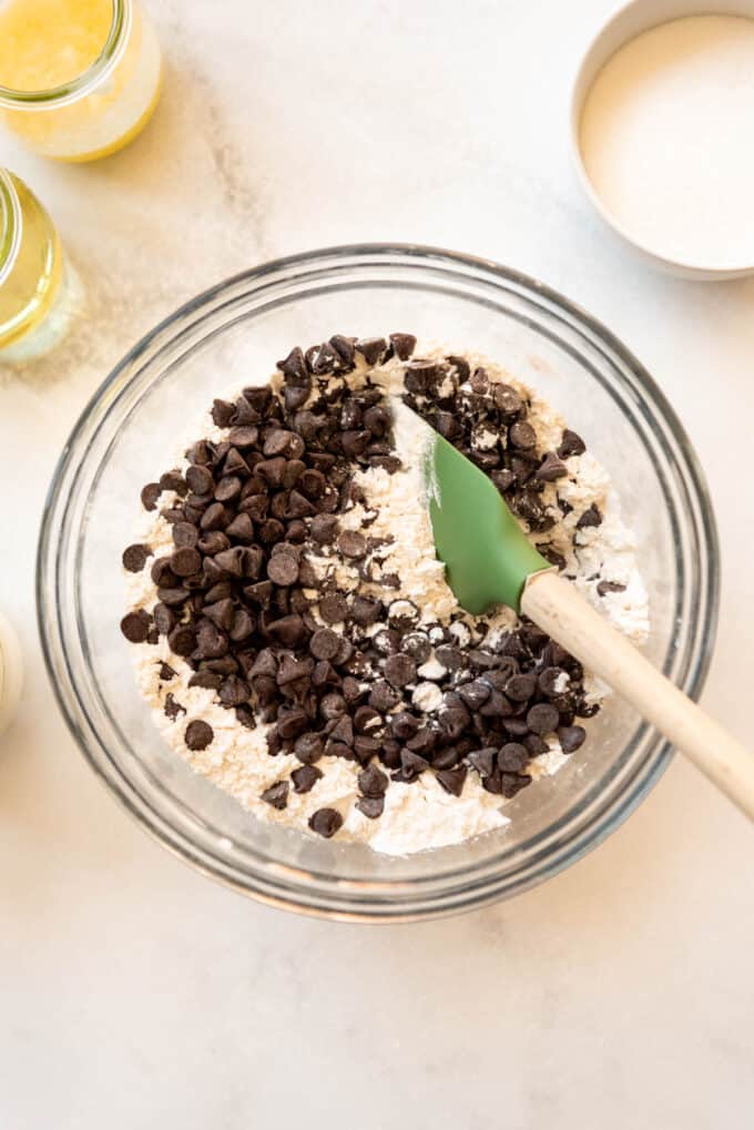 Stirring semisweet chocolate chips into dry ingredients with a spatula.