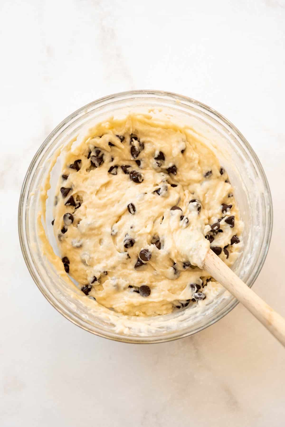 Chocolate chip muffin batter in a mixing bowl with a spoon.