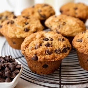 A square image of jumbo homemade chocolate chip muffins on a wire cooling rack.