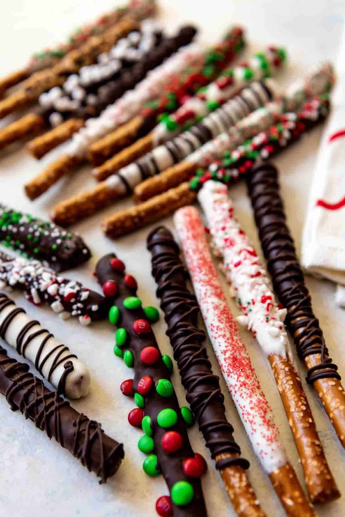 Christmas chocolate covered pretzel rods dipped in both semisweet and white chocolate, then covered with mini M&M's, sprinkles. and crushed candy cane bits!