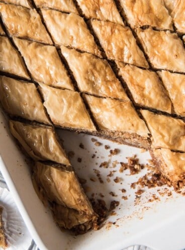 Greek Baklava in a baking dish cut into diamond shapes and a few pieces removed 