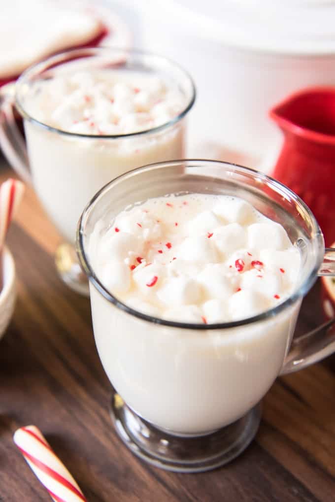 Glass mugs with peppermint white hot chocolate, topped with marshmallows and crushed candy cane sprinkles.