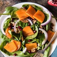 a festive persimmon and spinach salad with pomegrante seeds