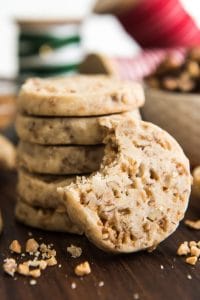 a stack of Toffee Pecan Shortbread Cookies with one leaning up on the side and missing a bite