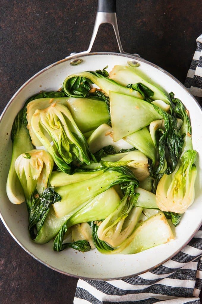Overhead view of a pan of bright green and white sauteed baby bok choy.