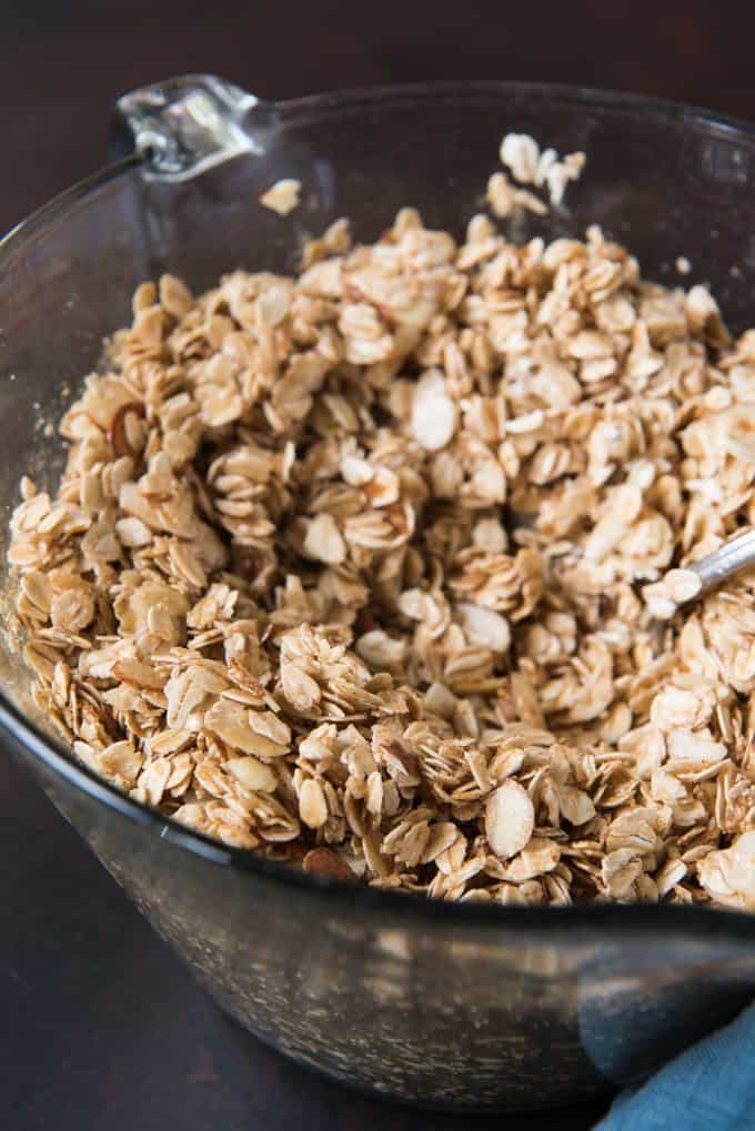 Bowl full of oats, almonds, honey, cinnamon, and vanilla for homemade granola.