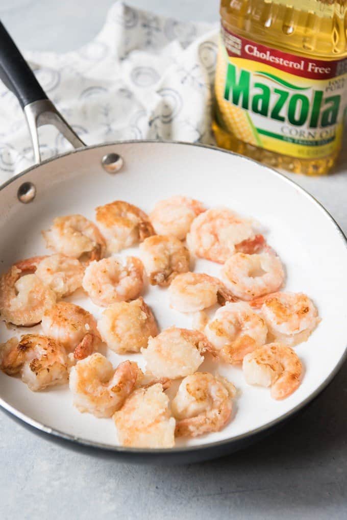 A pan full of crispy shrimp for honey walnut shrimp with a bottle of corn oil behind it.