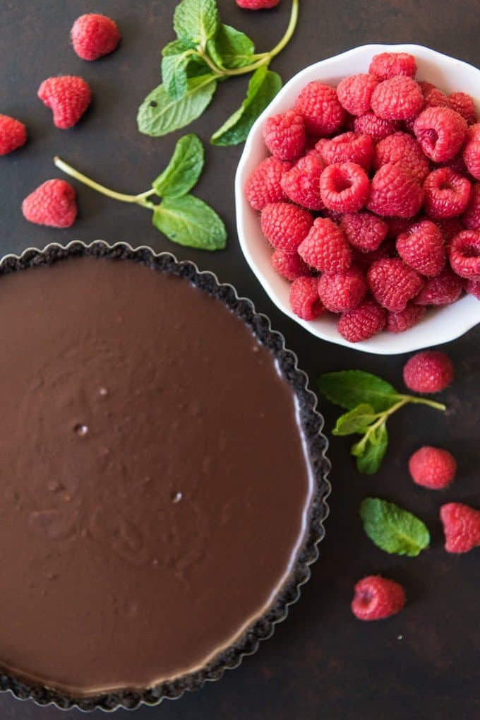 A smooth, rich chocolate ganache poured into a chocolate Oreo cookie crust and then toppped with lots of fresh red raspberries makes for a deceptively easy and decadent dessert in this Raspberry Chocolate Tart that's perfect for any celebration, but especially Valentine's Day!