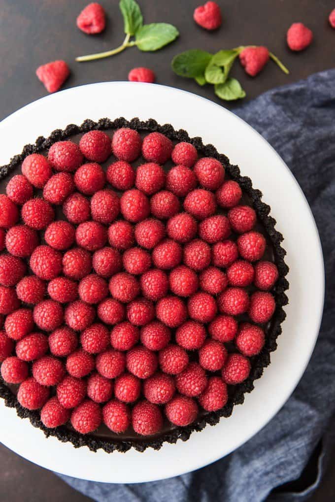 aerial view of raspberry rart on white cakestand with resh berries below