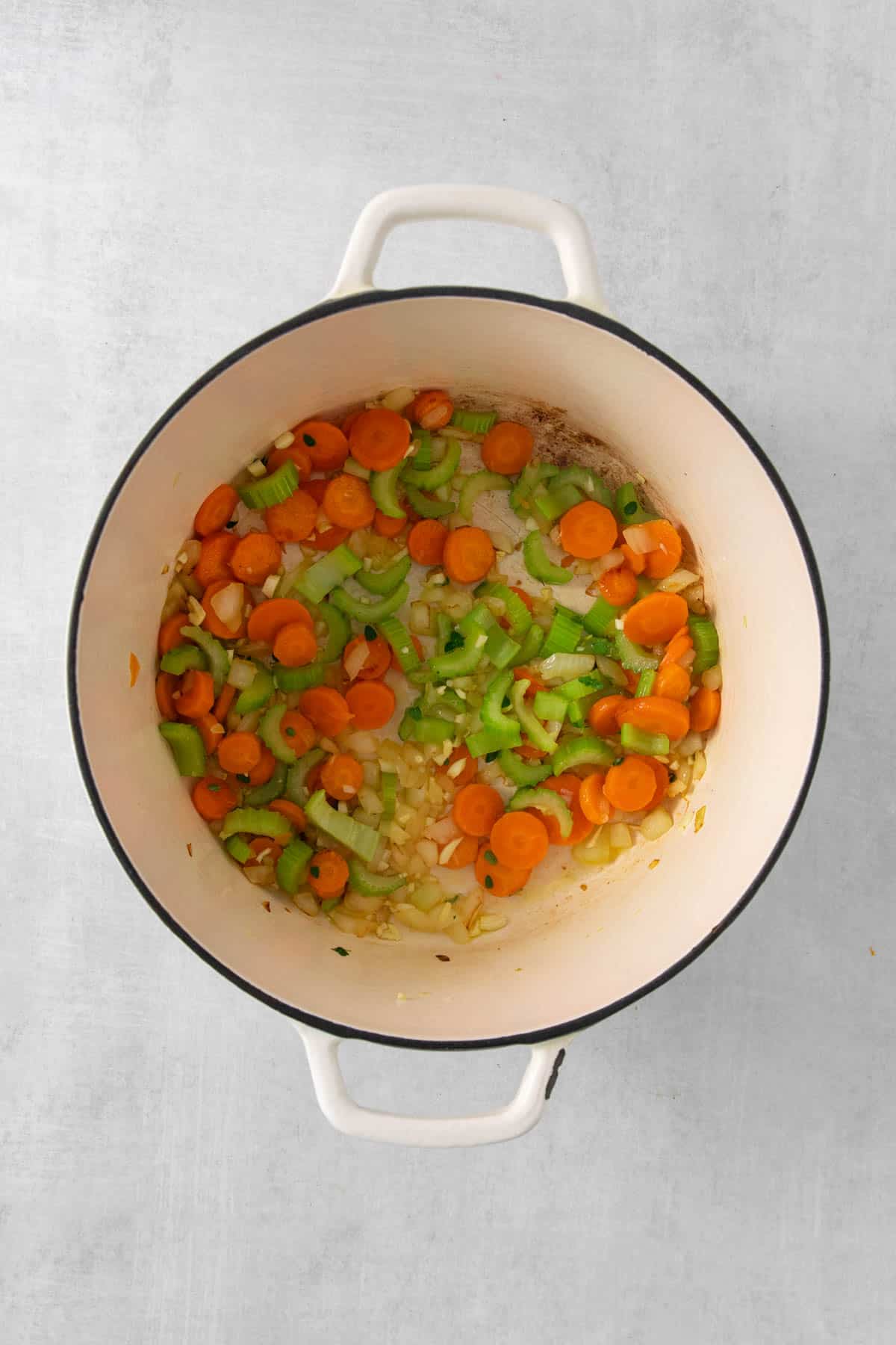 Sauteeing sliced carrots and celery in a large pot for split pea soup.