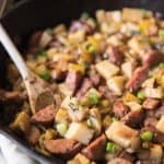 a wooden spoon in a skillet full of Sweet Potato Hash with Sausage & Apples