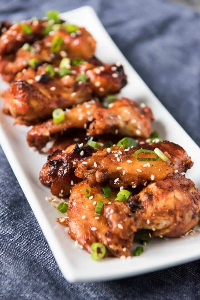 a row of baked korean bbq chicken wings on a white plate