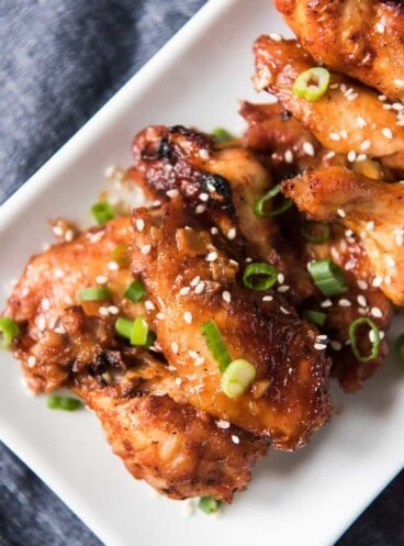 a close aerial shot of baked korean wings on a white plate