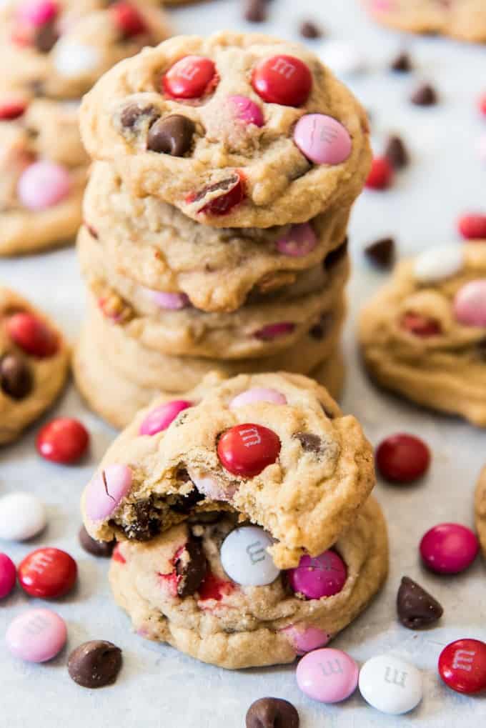 A stack of the best soft & chewy M&M cookies with the top cookie having a bite already taken out of it.