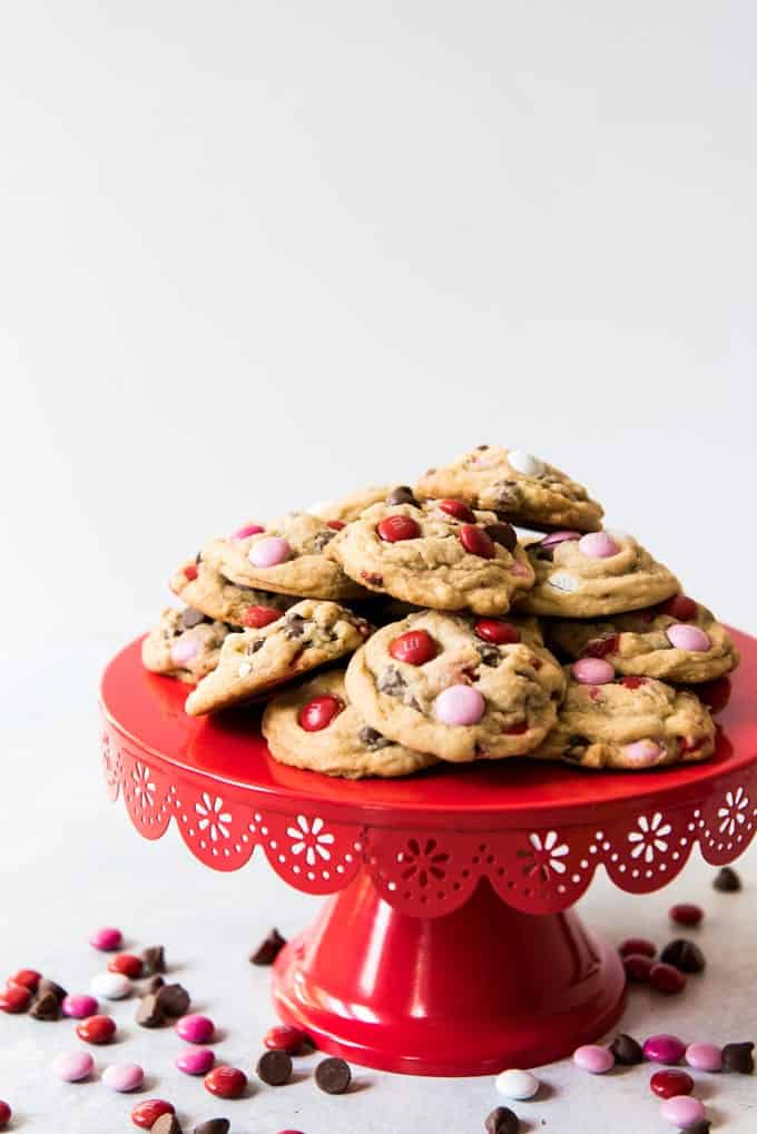 m&m cookies on a red cakestand with scattered candies around it