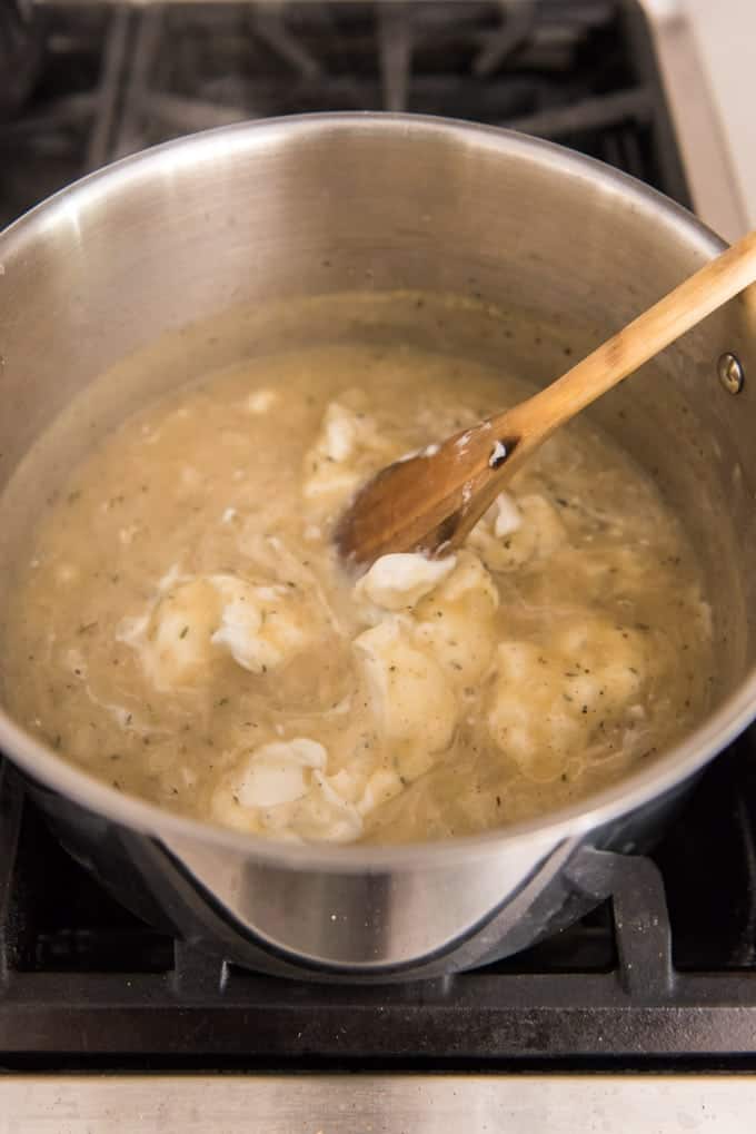 Sour cream being stirred into homemade cream of chicken soup.