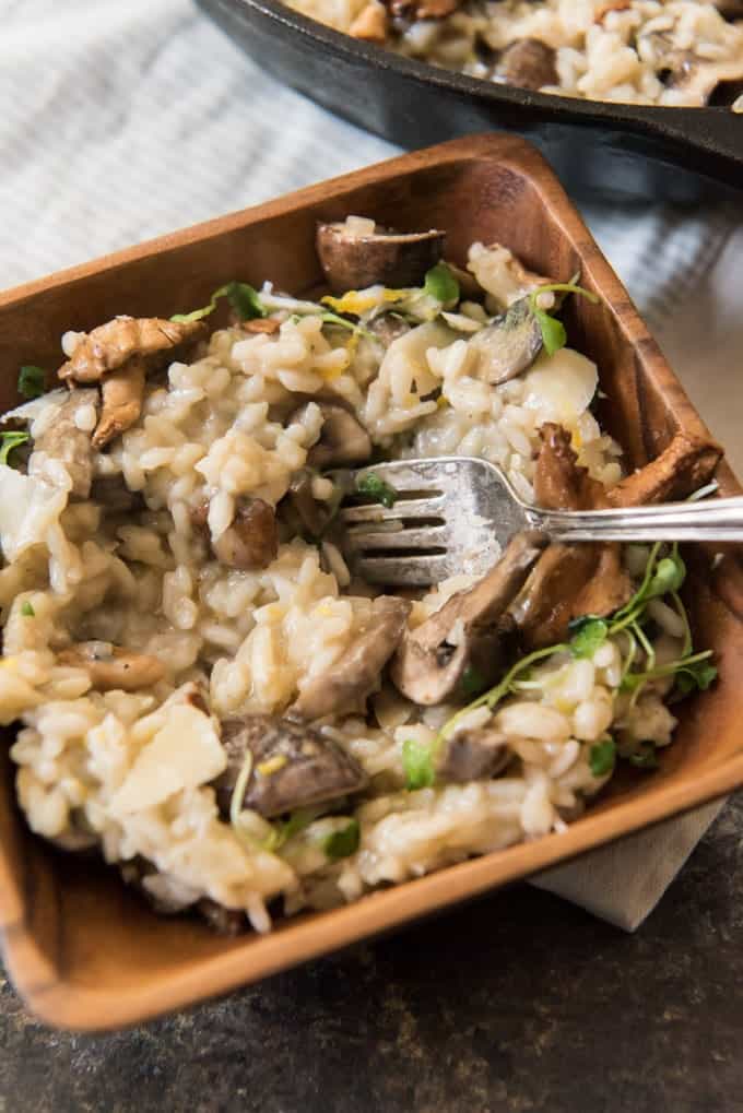 a wooden bowl filled with creamy roasted garlic and mushroom risotto