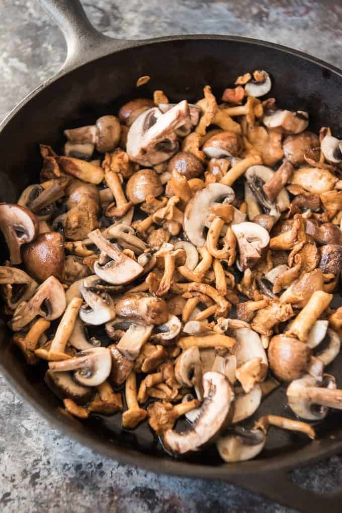 Hedgehog and crimini mushrooms are sauteed in a cast iron skillet with a little olive oil to go into a creamy mushroom risotto recipe.