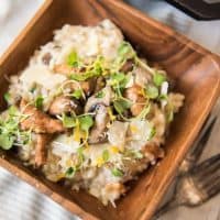a square wooden bowl filled with creamy mushroom risotto