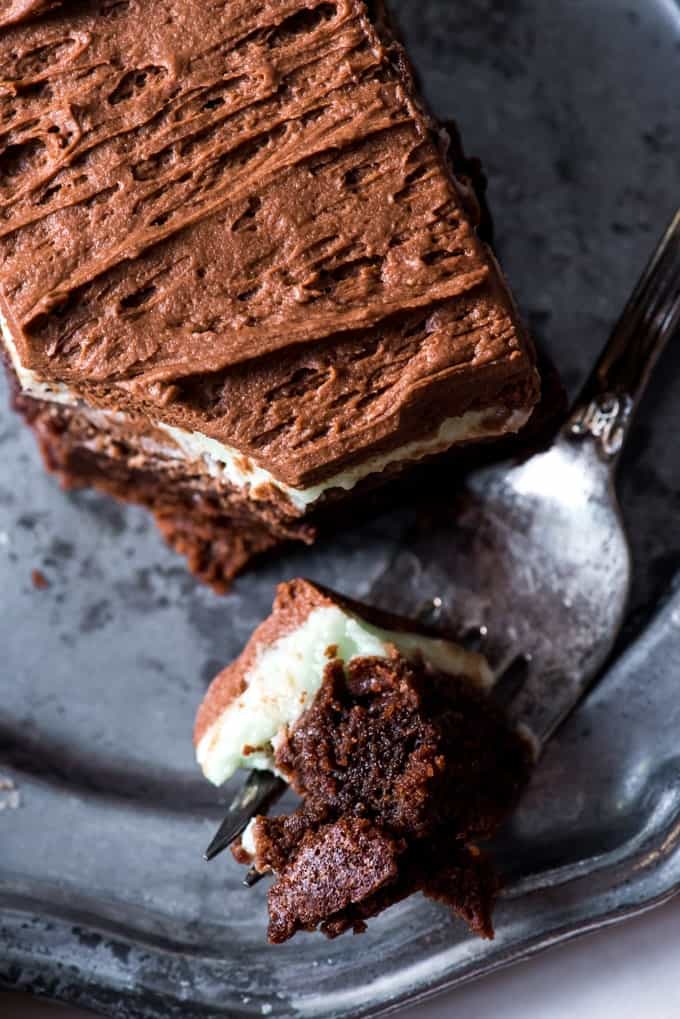 a fork full of frosted mint brownie on a plate