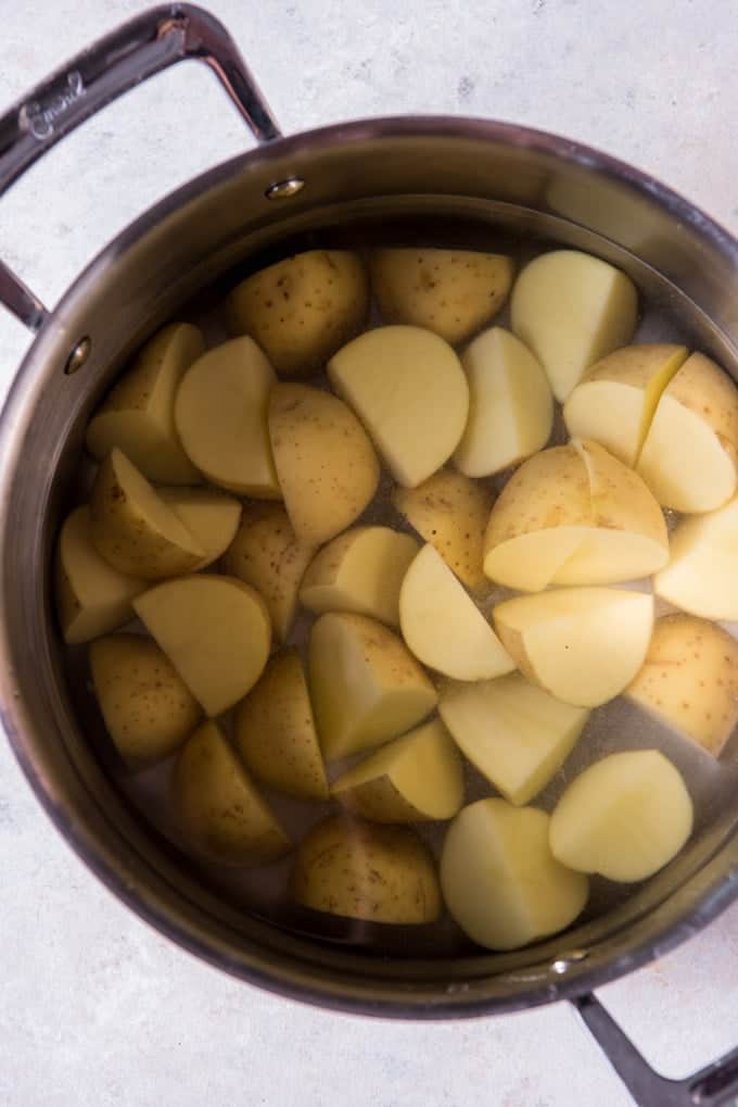 A large pot of salted water with cut up yukon gold potatoes for boiling and mashing into Irish colcannon.