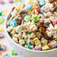 A bowl of Lucky Charms snack mix with pretzels, popcorn, lucky charms cereal, M&M's, and white chocolate.