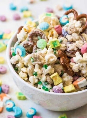 A bowl of Lucky Charms snack mix with pretzels, popcorn, lucky charms cereal, M&M's, and white chocolate.