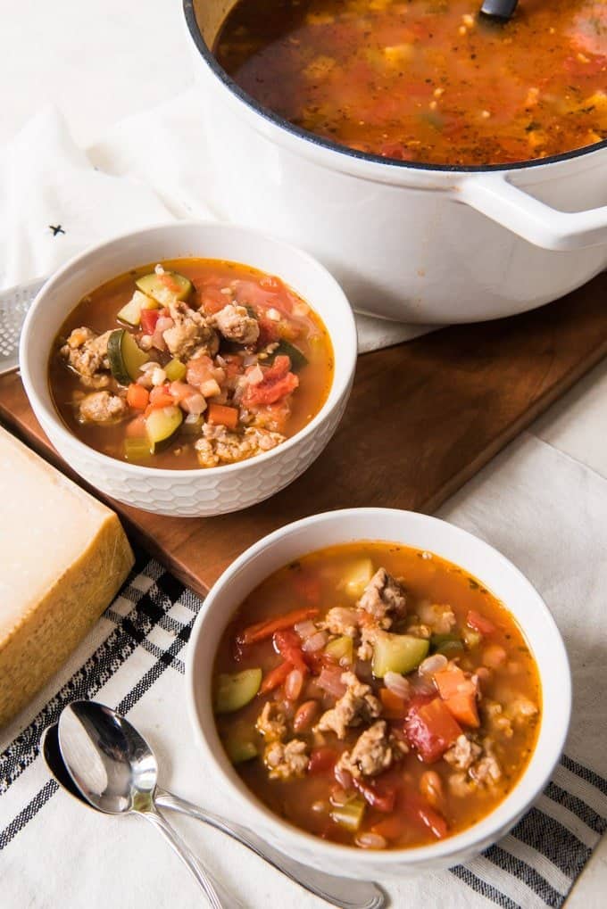 two bowls of minestrone soup next to a pot with more inside