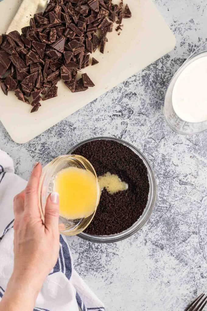 Pouring melted butter into Oreo cookie crumbs.