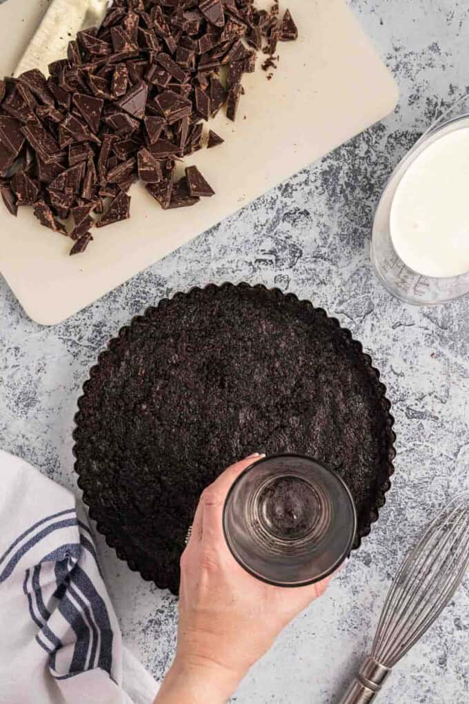 Pressing an Oreo crust into a tart pan.