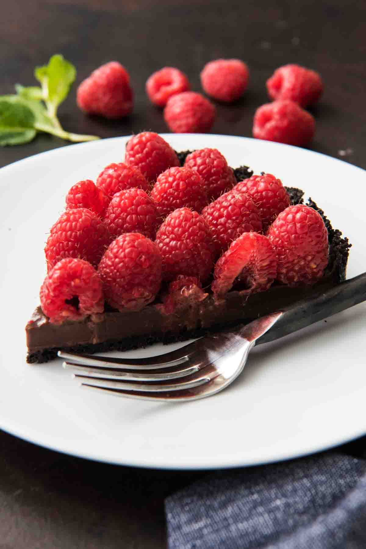 A slice of raspberry chocolate tart on a white plate.