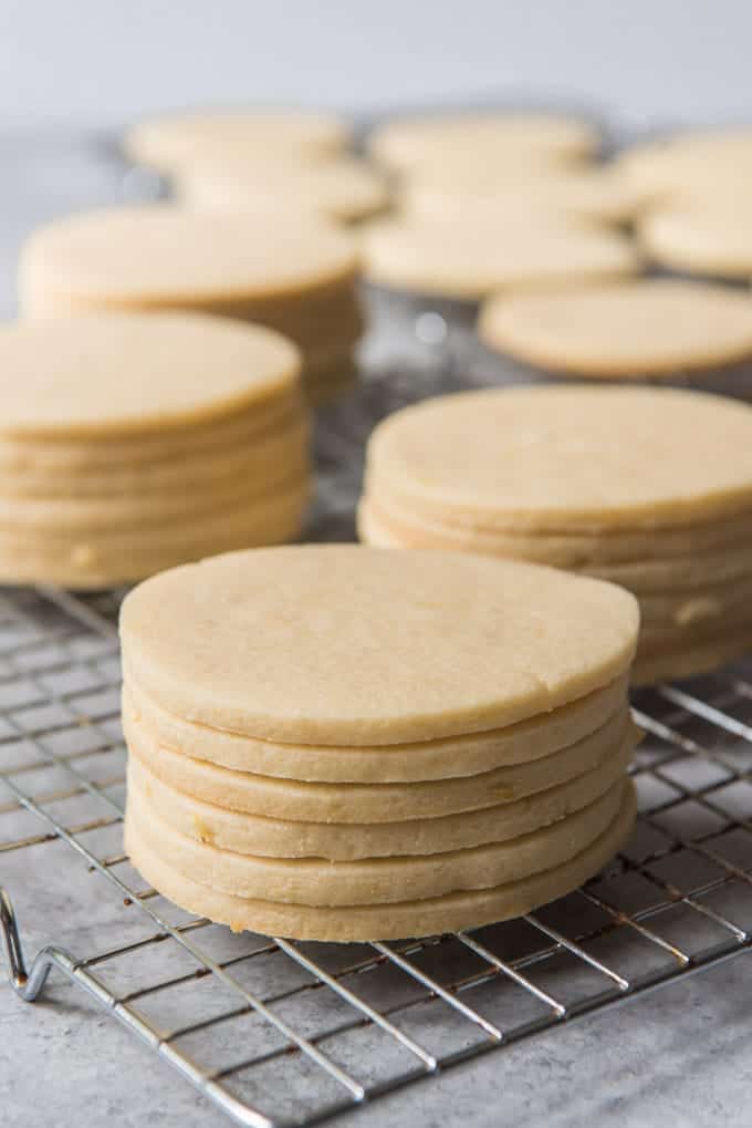 Stacks of unfrosted sugar cookies cooling on a wire rack.