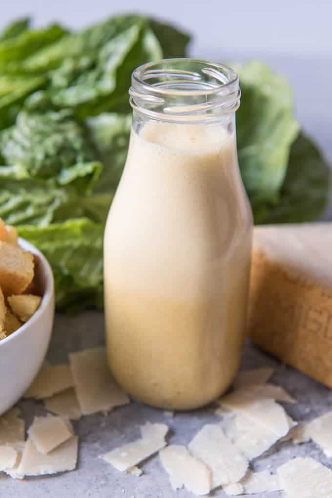 An image of a glass jar of homemade caesar salad dressing made with anchovies. 