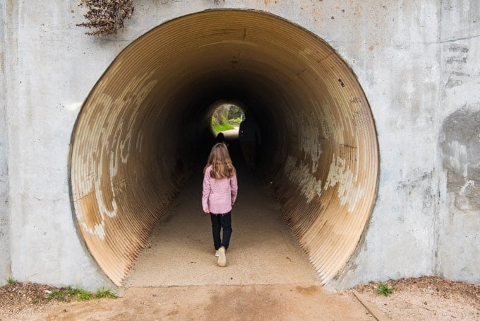 An image of a young child walking into a culvert tunnel.