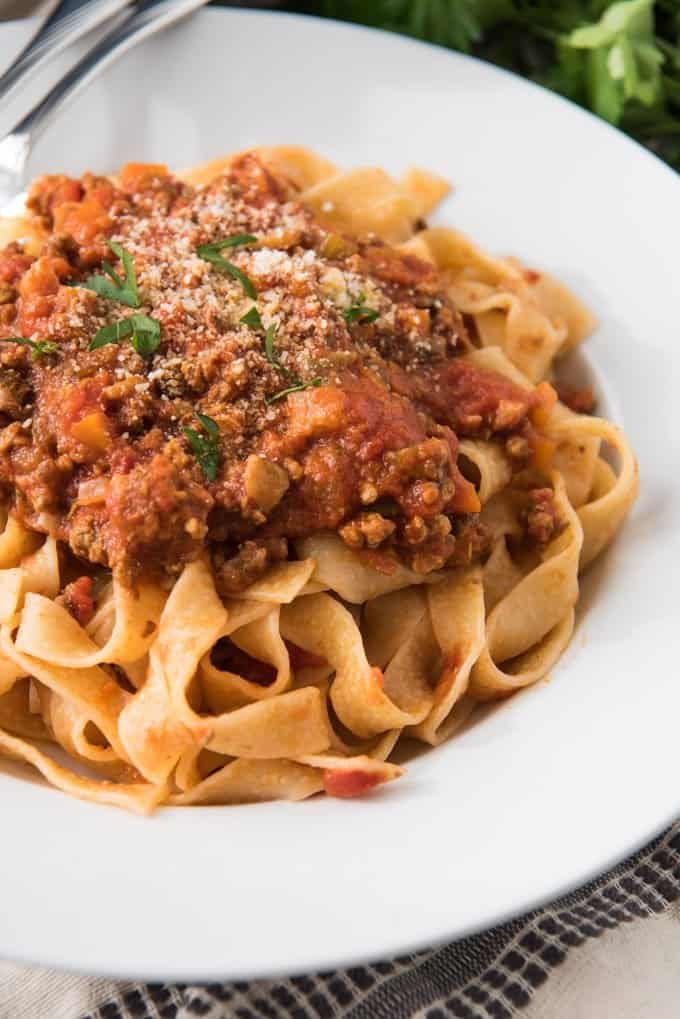 An image of tagliatelle pasta with meaty mushroom bolognese sauce, sprinkled with Parmesan cheese.