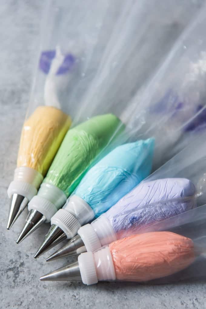 Five bags of royal icing dyed in pastel hues with tips and couplers for decorating sugar cookies with royal icing.