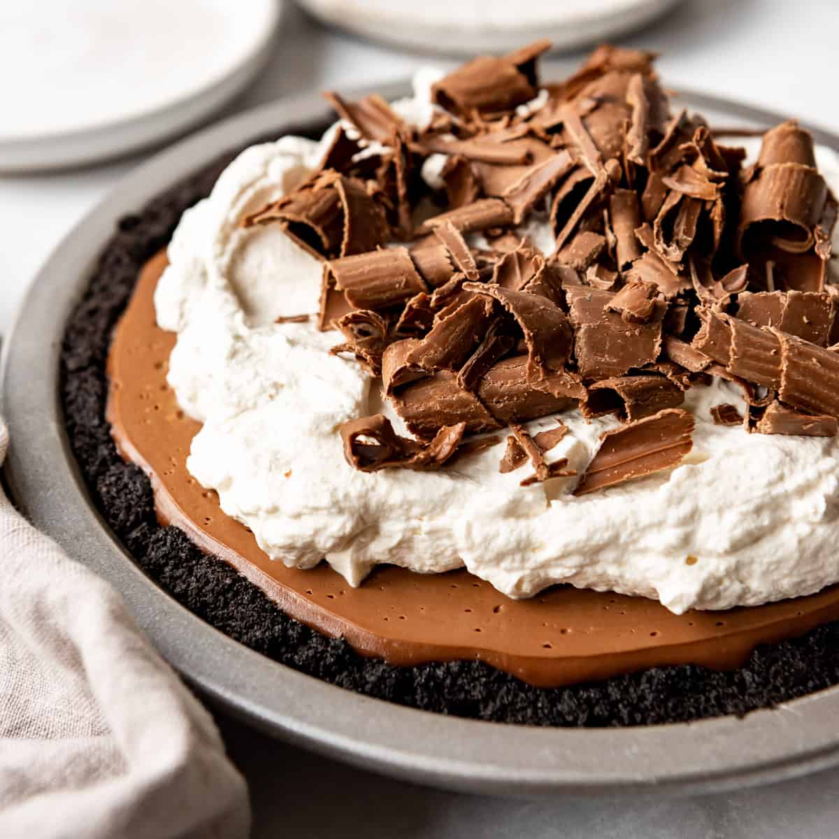 A homemade chocolate cream pie in a metal pan topped with whipped cream and chocolate curls.