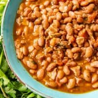 An image of a blue bowl full of charro beans (also known as frijoles charros or cowboy beans) made in a pressure cooker.