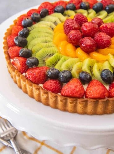 a fresh and colorful french fruit tart on a white cakestand