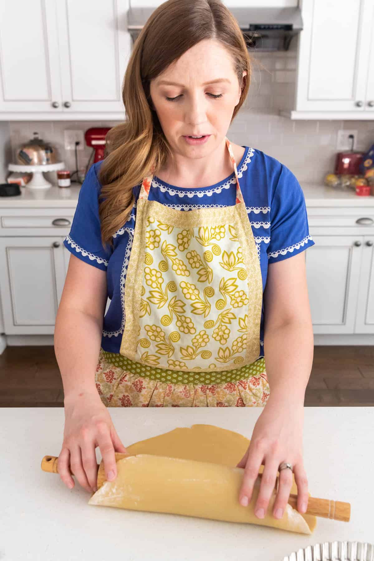 An image of a woman rolling out a sweet pastry crust for a French fruit tart.