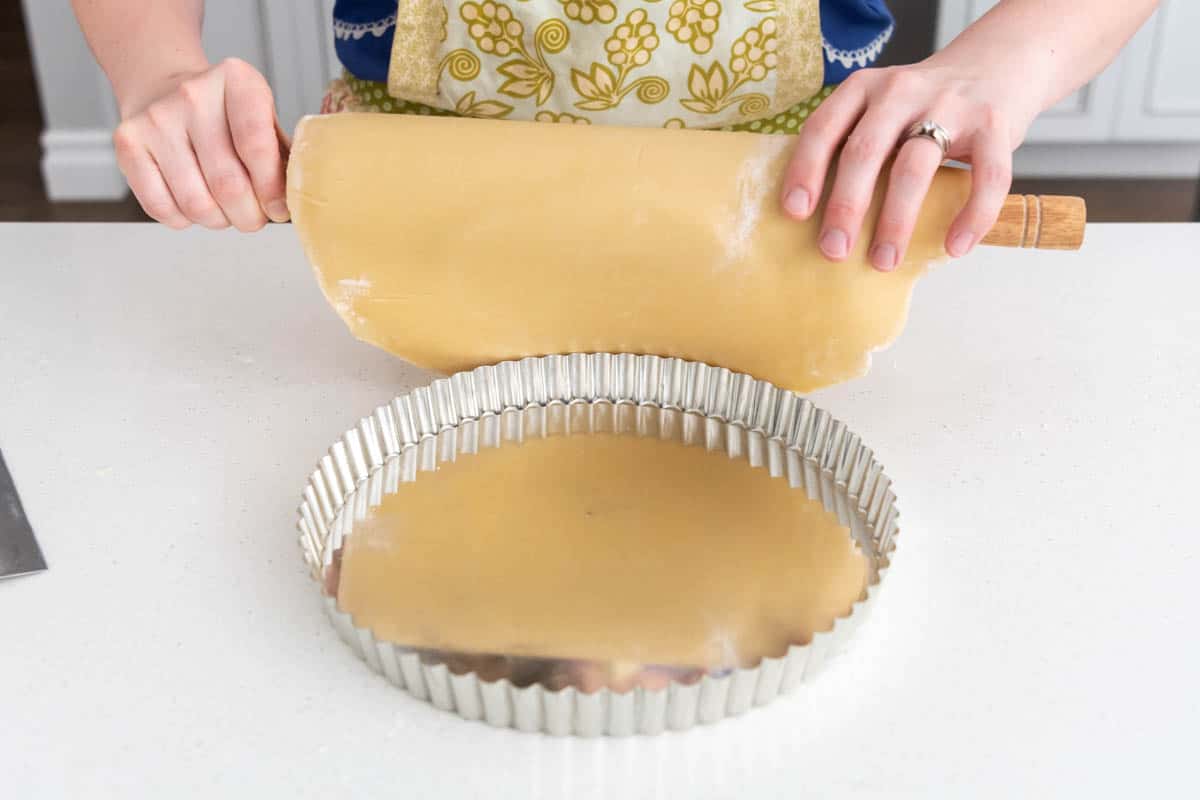 Lifting a French tart pastry crust onto a tart pan.