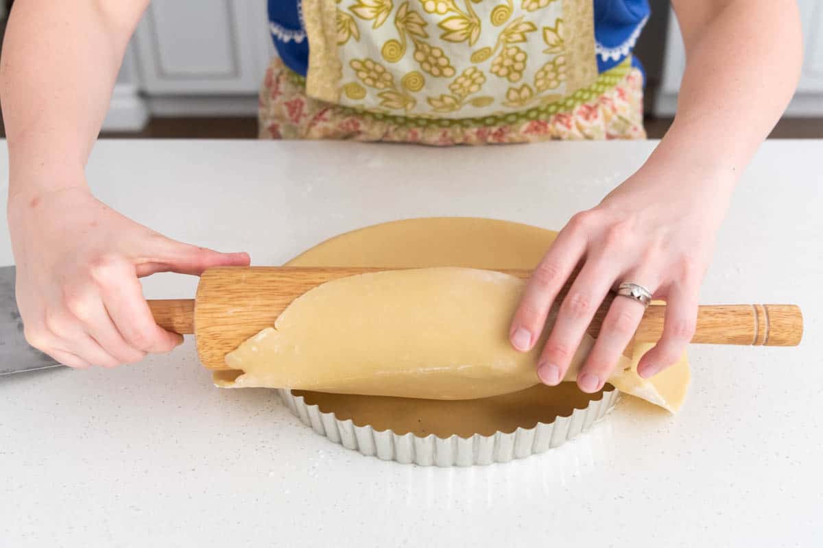 Rolling tart dough into a large tart pan.