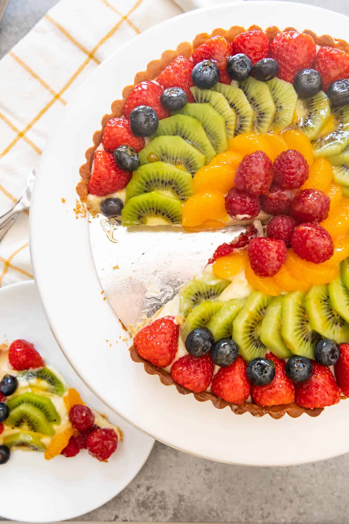 An image of a classic French fruit tart with strawberries, kiwi, mandarin oranges, blueberries and raspberries arranged on top.