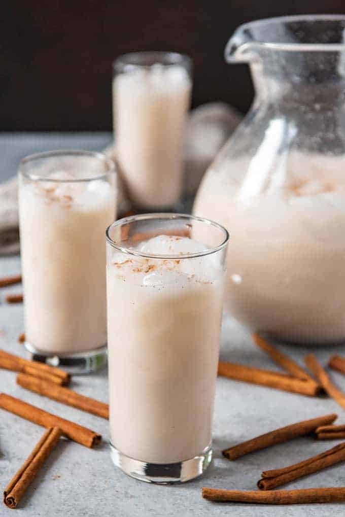 An images of glasses of homemade horchata made from an easy horchata recipe, surrounded by sticks of cinnamon.