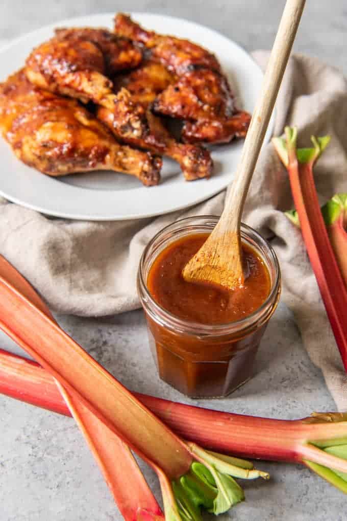 a glass jar full of rhubarb bbq sauce with a wooden spoon stuck inside