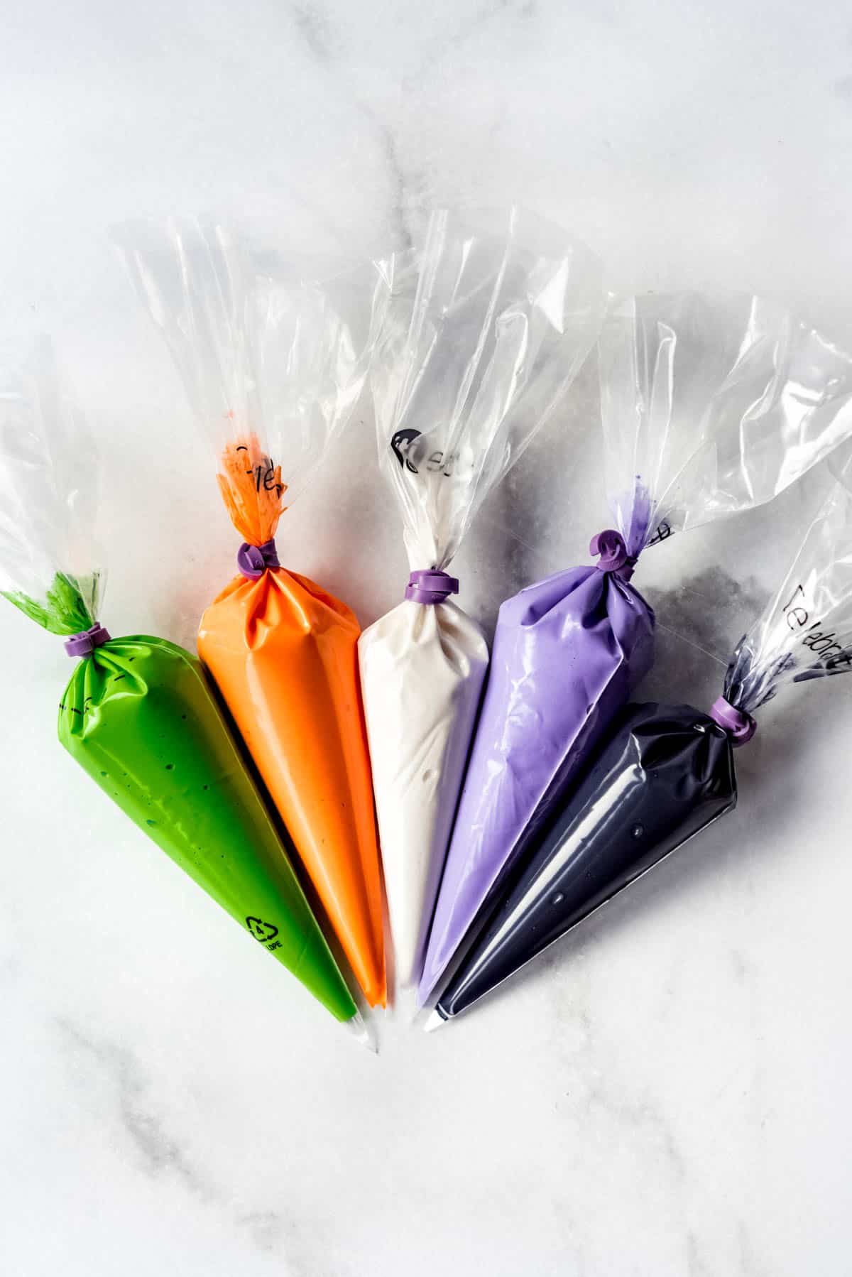 Give bags of royal icing in green, orange, white, purple and black.