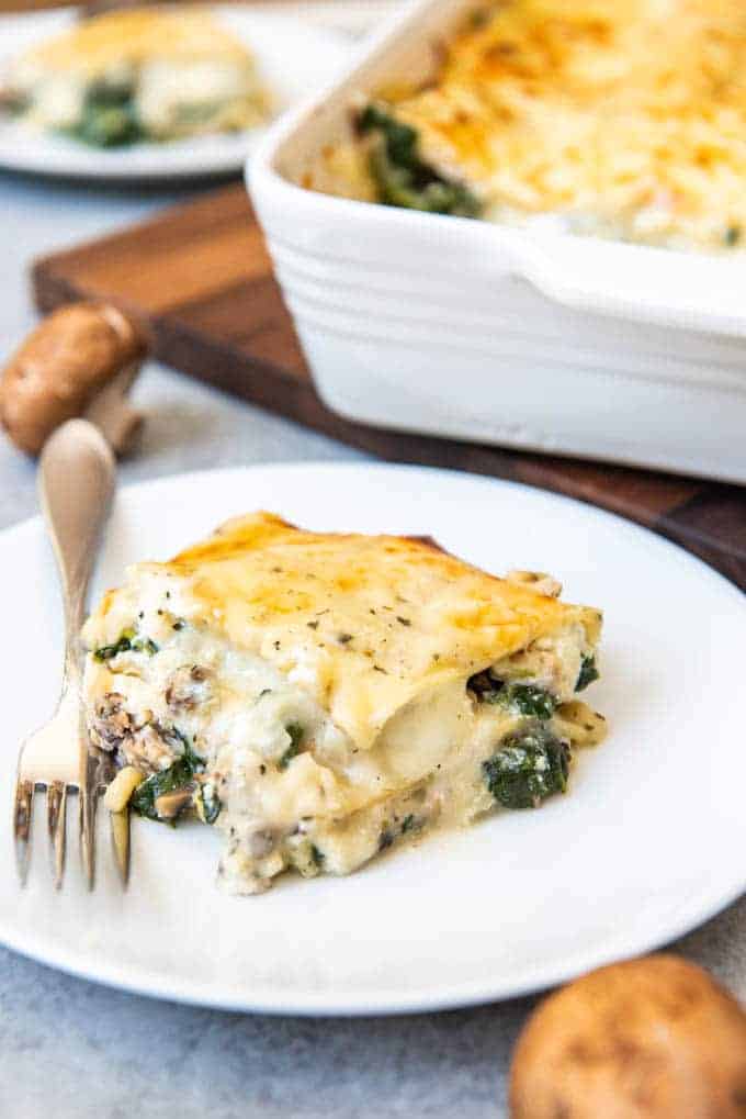 An image of a slice of chicken spinach lasagna made with a white sauce, cheese, and mushrooms.